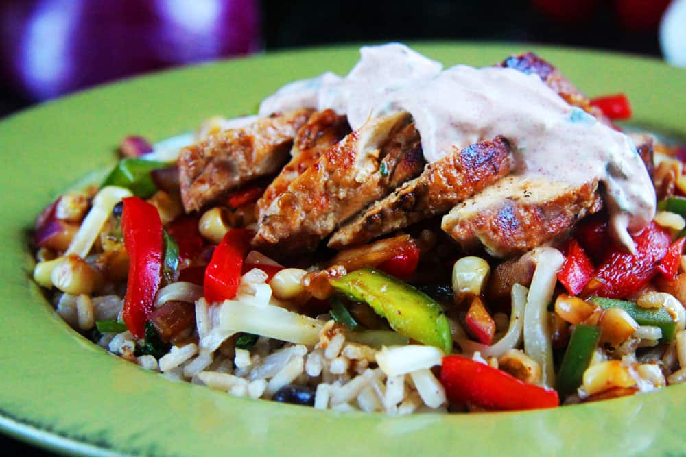 chicken fajita bowls with sliced chicken lined in a row on top of rice