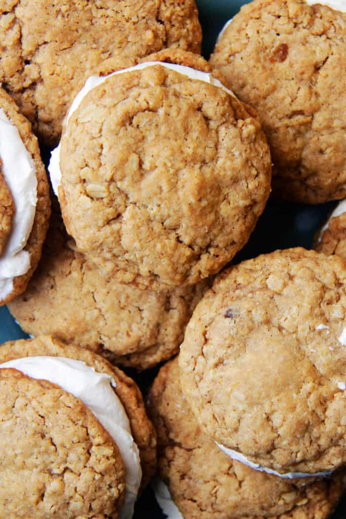 These Little Debbie's Oatmeal Cream Pies copycat are melt-in-your-mouth addicting. The cookies are bursting with buttery, chewy, brown sugar, molasses oatmeal which sand which a luscious creamy vanilla center. After one bite, you will never want to buy Little Debbies' Oatmeal Cream Pies ever again! top view of homemade oatmeal cream pies with cream filling