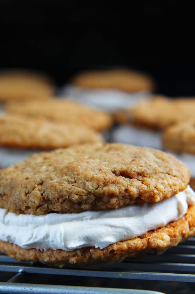 These Little Debbie's Oatmeal Cream Pies copycat are melt-in-your-mouth addicting. The cookies are bursting with buttery, chewy, brown sugar, molasses oatmeal which sand which a luscious creamy vanilla center. After one bite, you will never want to buy Little Debbies' Oatmeal Cream Pies ever again! up close of chewy oatmeal cream pies with cream filling