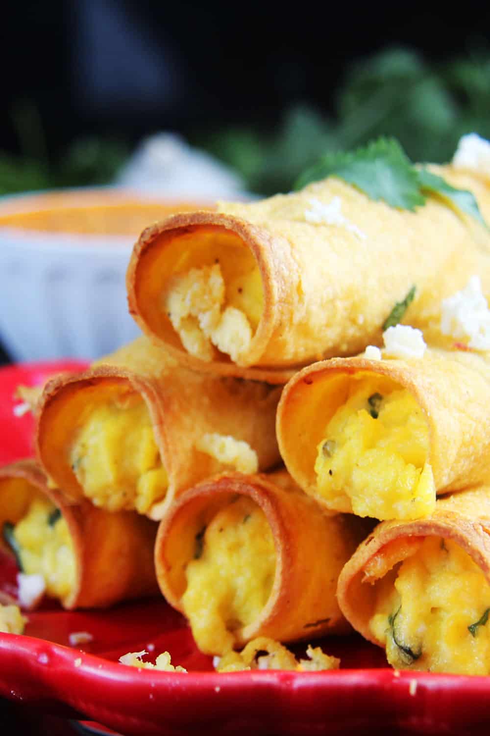 Close up photo of Breakfast Taquitos on a red plate stacked up.