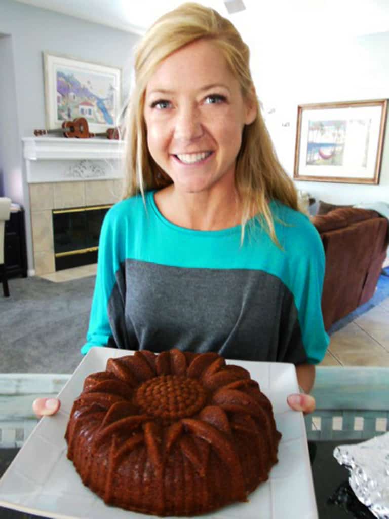 Woman holding brown sugar caramel pound cake on white platter.