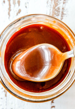 top view of a spoon dipping into easy caramel sauce in a jar