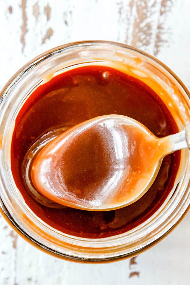 top view of a spoon dipping into easy caramel sauce in a jar