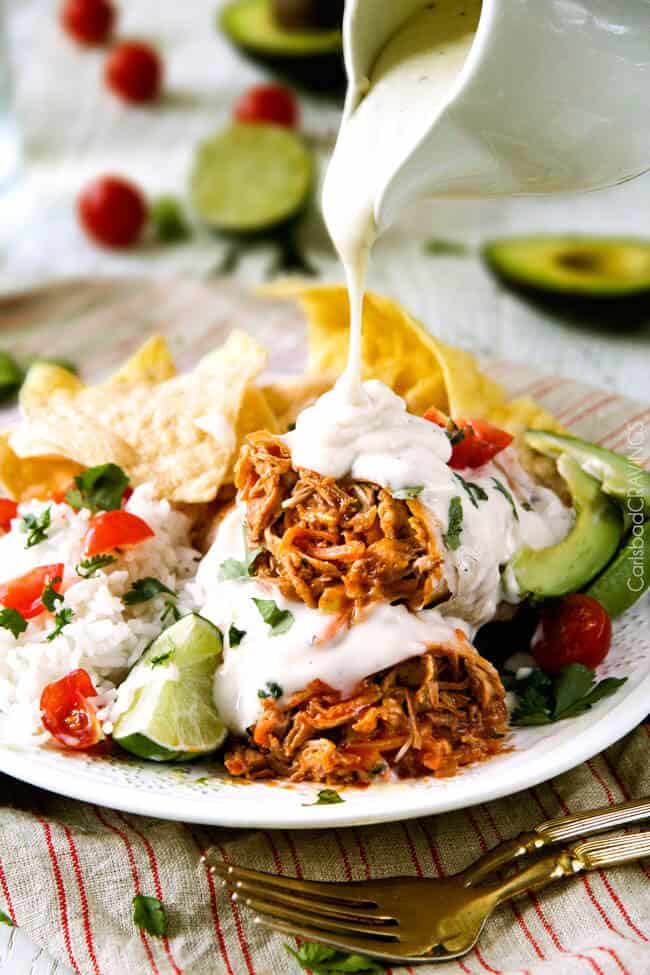 Fininshed Smothered Buffalo Chicken Baked Burritos pouring the Creamy Lime Ranch Sauce over top.