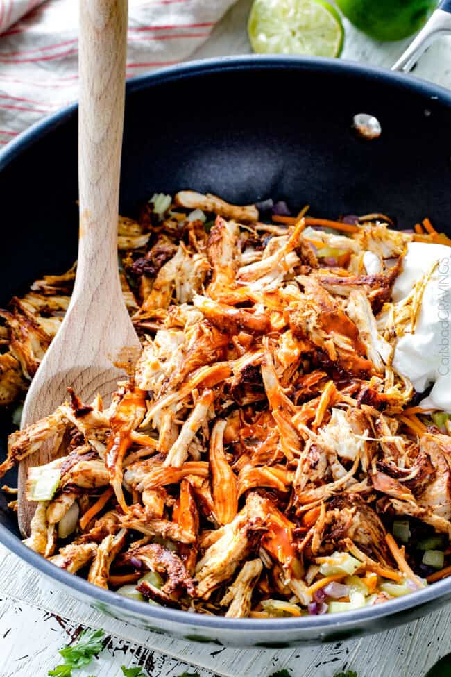 Showing how to make Smothered Buffalo Chicken Baked Burritos by adding chicken to the pan.
