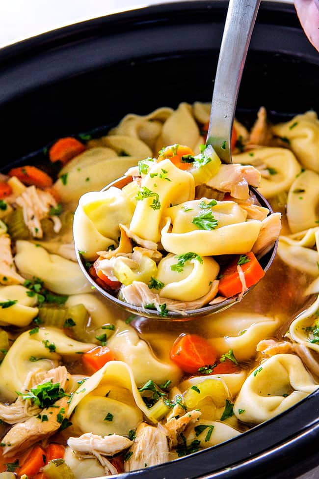 This is the BEST Slow Cooker Chicken Tortellini Soup you will ever try! It's super easy, seasoned to perfection and a comforting, satisfying dinner any night of the week! side view of Chicken Tortellini Soup with cheese tortellini, carrots, celery, onions, garlic and spicess