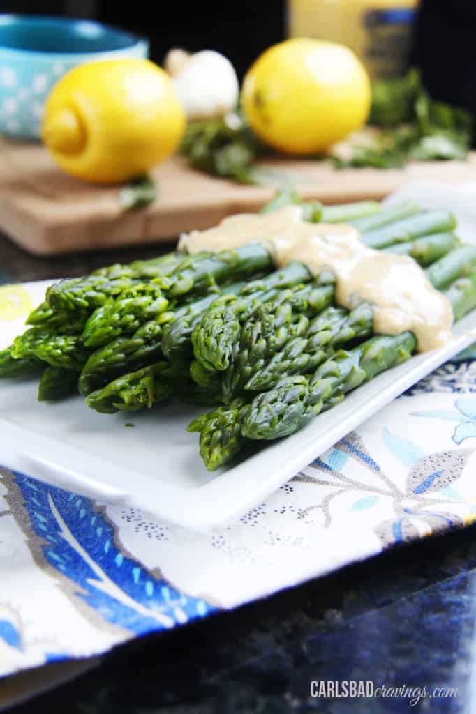 Skinny guilt free Healthy Hollandaise Sauce over asparagus on a white plate