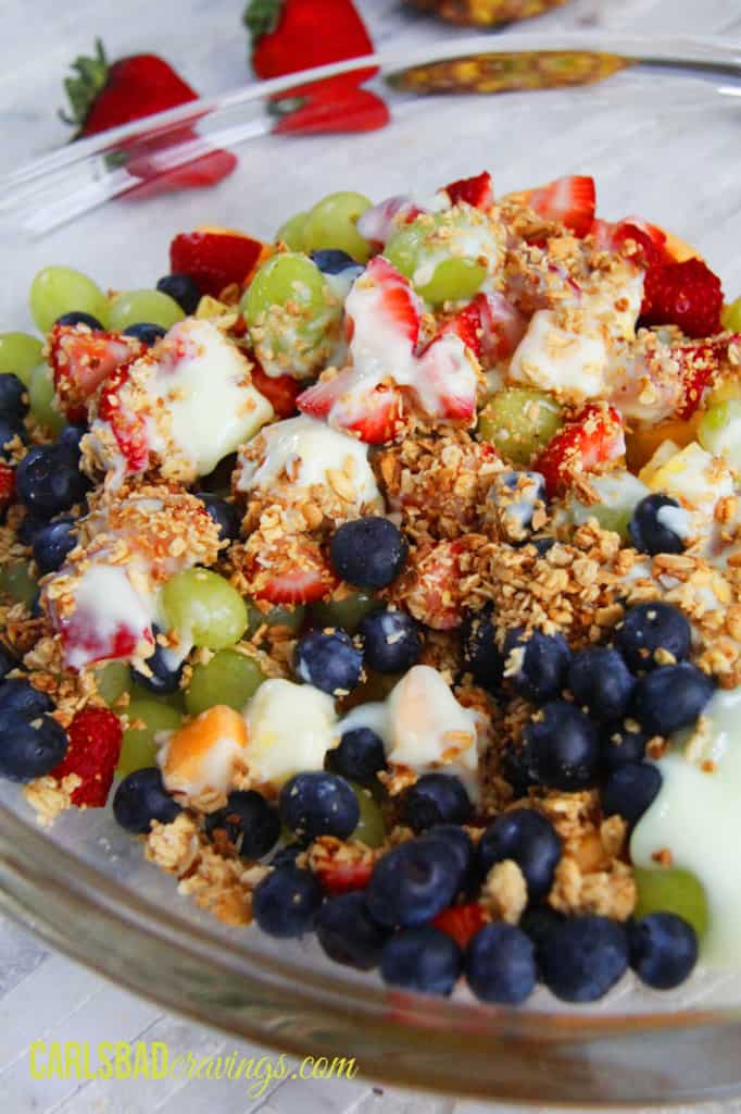 fruit salad with yogurt in a glass bowl with pineapple, strawberries, grapes, blueberries