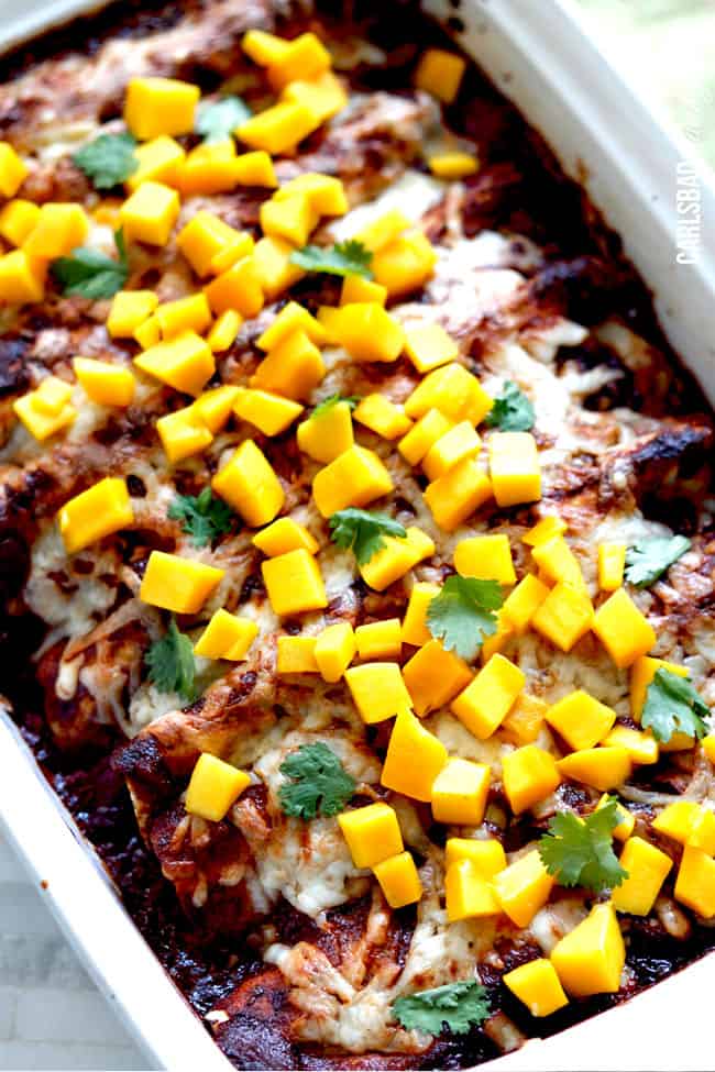 Showing baked Chipotle Chicken Enchiladas with mango in a casserole dish.