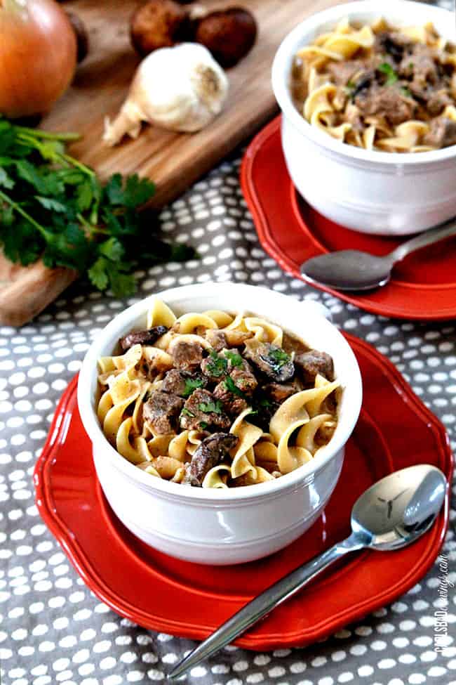 Beef Stroganoff Soup in a white with steak and parsley on top of egg noodles.