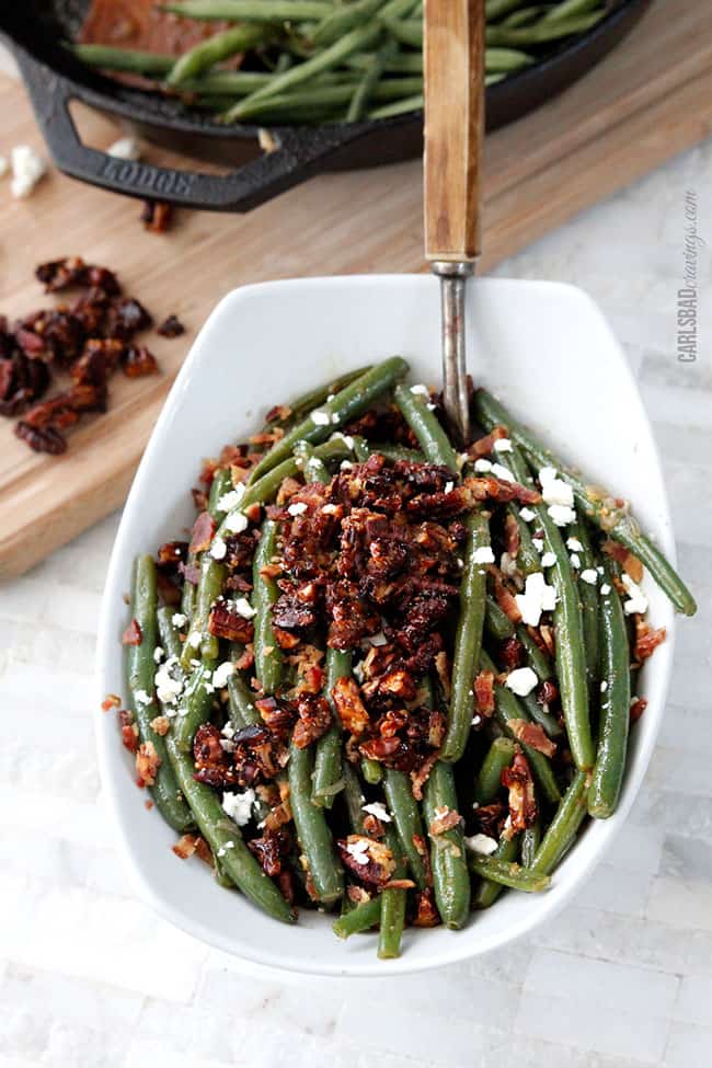 Dijon Maple Green Beans with Caramelized Pecans, Bacon and Feta | these aren't your grandmother's green beans! Tangy, salty, sweet, crunchy, crispy, creamy AKA, “the best green beans ever.” Not just for Thanksgiving but a year round company pleasing, delicious side. front view of green beans recipe with bacon and pecans with a wood serving spoon