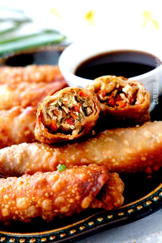 BEST egg rolls I've ever made or had and so fast made with premade skillet sauce and food processor hack! I am bringing these to all my holiday parties! a baked chicken egg roll cut open so you can see the chicken and vegetable filling