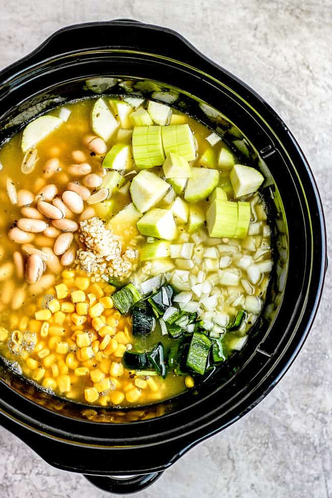 showing how to make crockpot chicken tortilla soup by adding chicken, chicken broth, beans, corn, peppers to a slow cooker