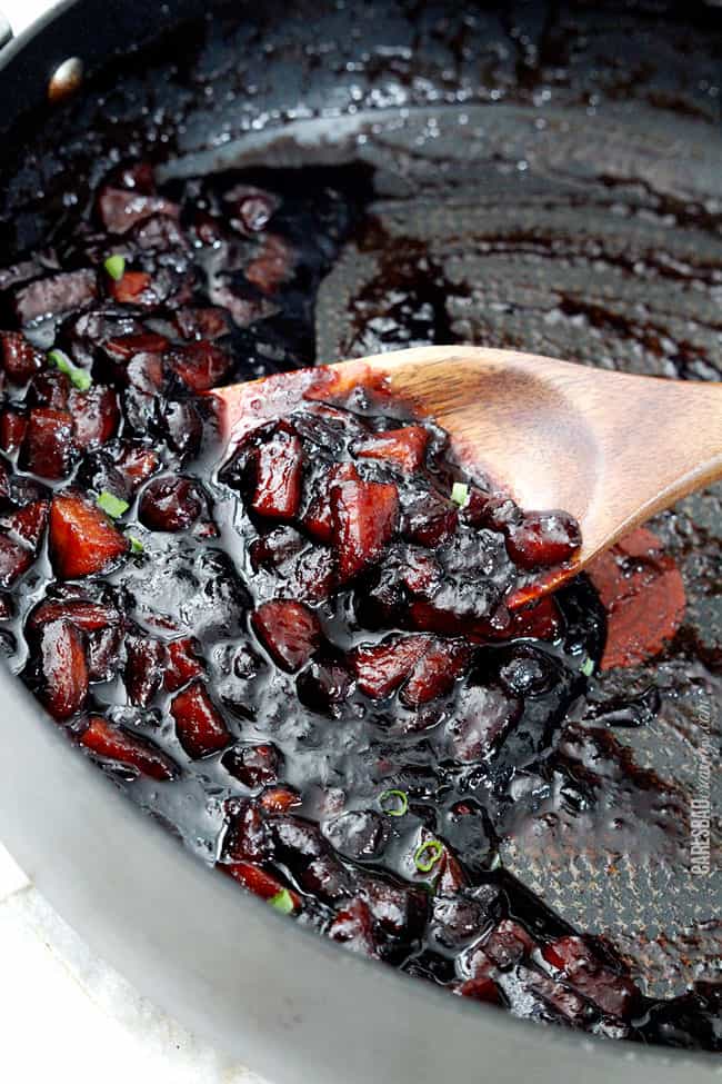 A close up shot showing the reduced sauce for the Cajun Pork Tenderloin in a pan with wood spoon.