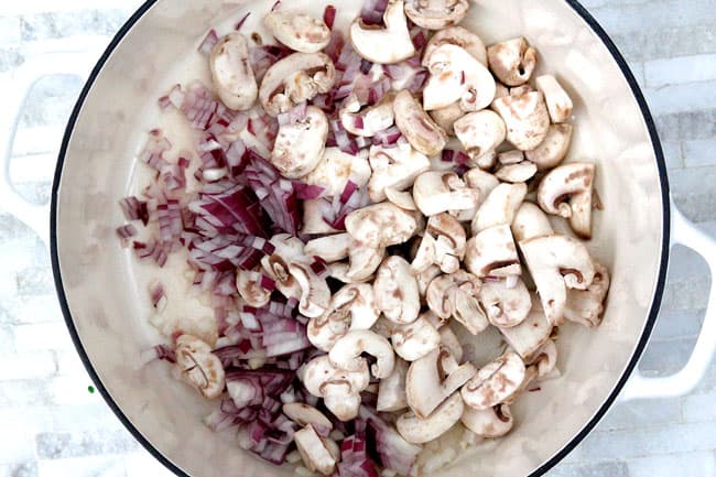 Showing how to make Cajun Chicken Pasta Soup in a white pot adding mushrooms and onions in cream.