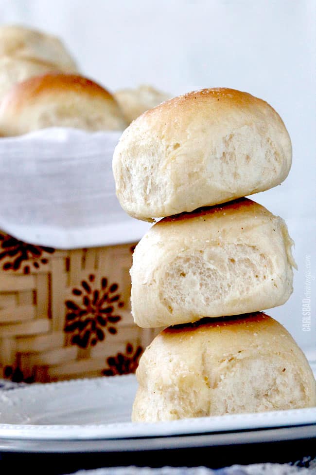 Three homemade Dinner Rolls stacked on top of each other on a white serving plate.