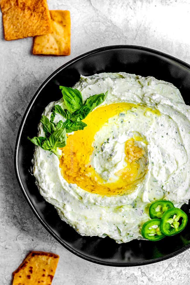 top view of spicy whipped feta dip in a black bowl with crackers