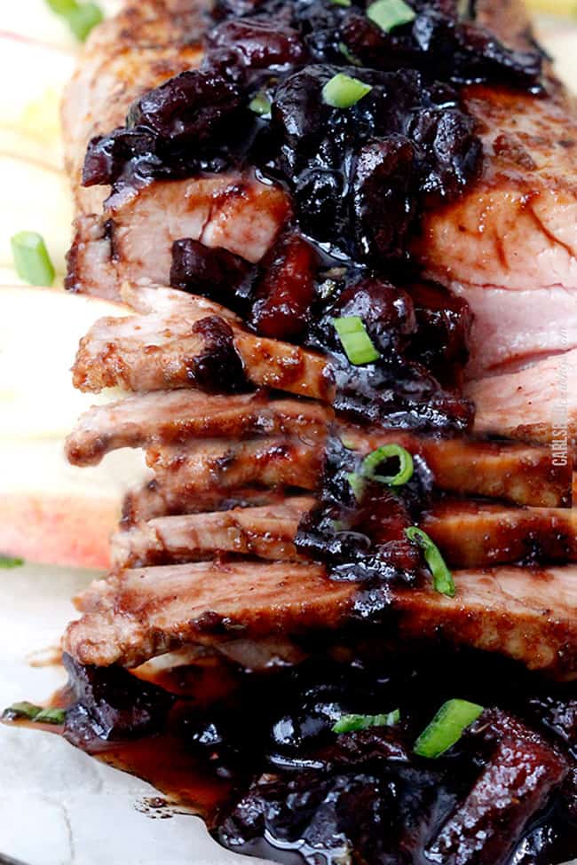 Close up shot of Cajun Pork Tenderloin sliced and displayed with glaze garnished with chives.