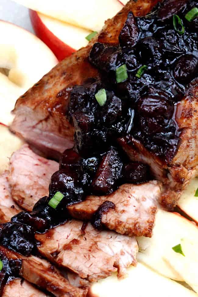 Top view of Cajun Pork Tenderloin sliced and displayed with glaze garnished with chives.