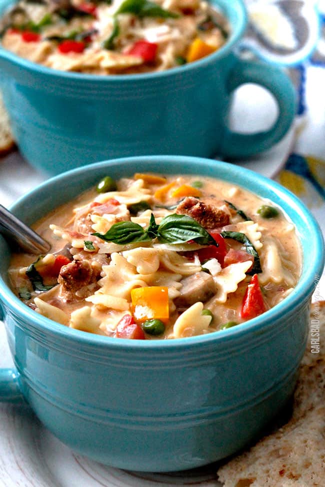 Finished dish of Cajun Chicken Pasta Soup served in a teal bowl with a spoon and basil garnish.