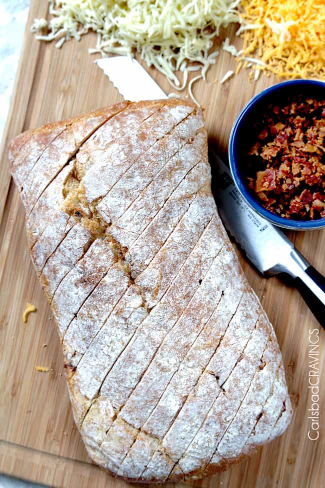 Showing how to make Bacon Ranch Pepper Jack Pull Apart Bread by cutting lines in bread to fill toppings.