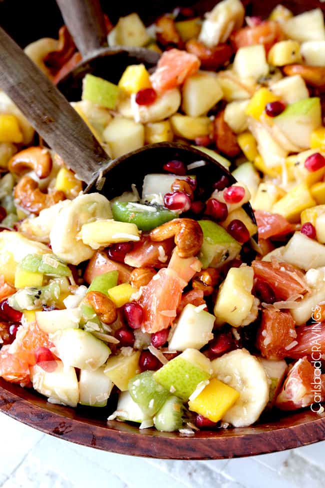 showing how to make tropical fruit salad by tossing fruit together