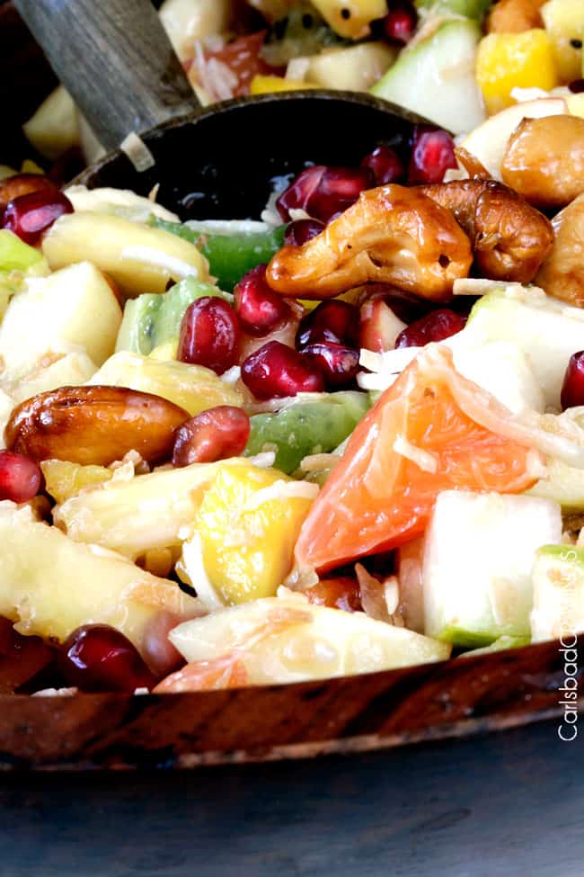 showing how to make tropical fruit salad by tossing fruit together