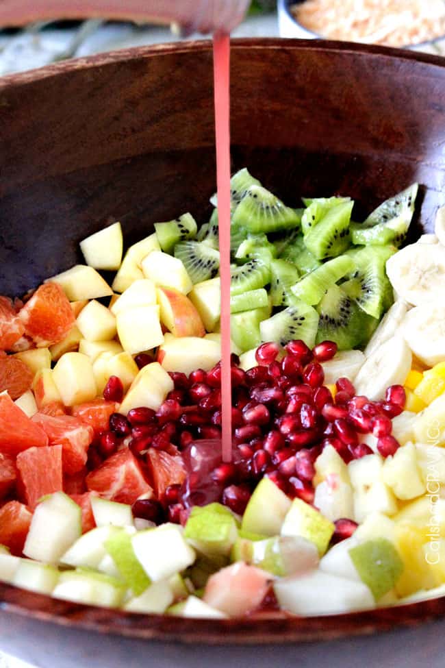 showing how to make tropical fruit salad by adding pomegranate dressing