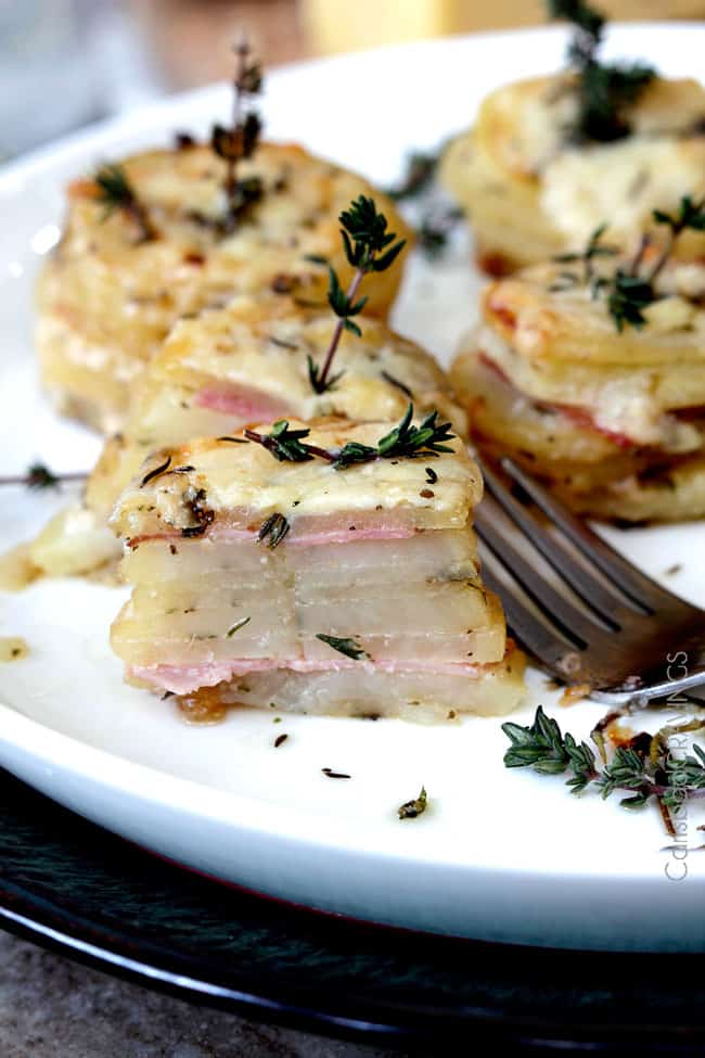 ham and potato stacks on a white plate. the front stack has been cut in half to show the layers.