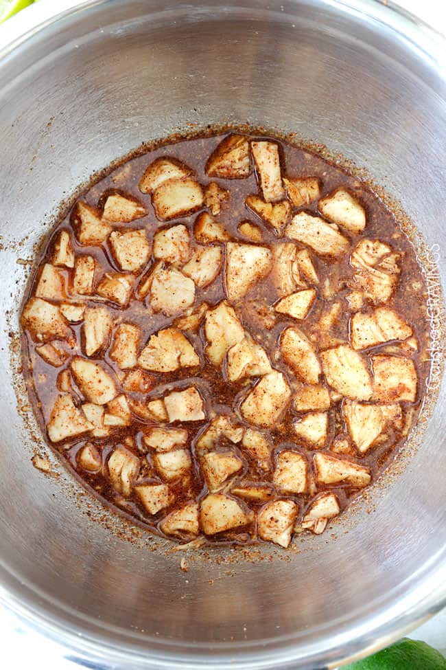 Showing how to make Salsa Verde Honey Lime Chicken by marinating the raw chicken in a stainless steel bowl.