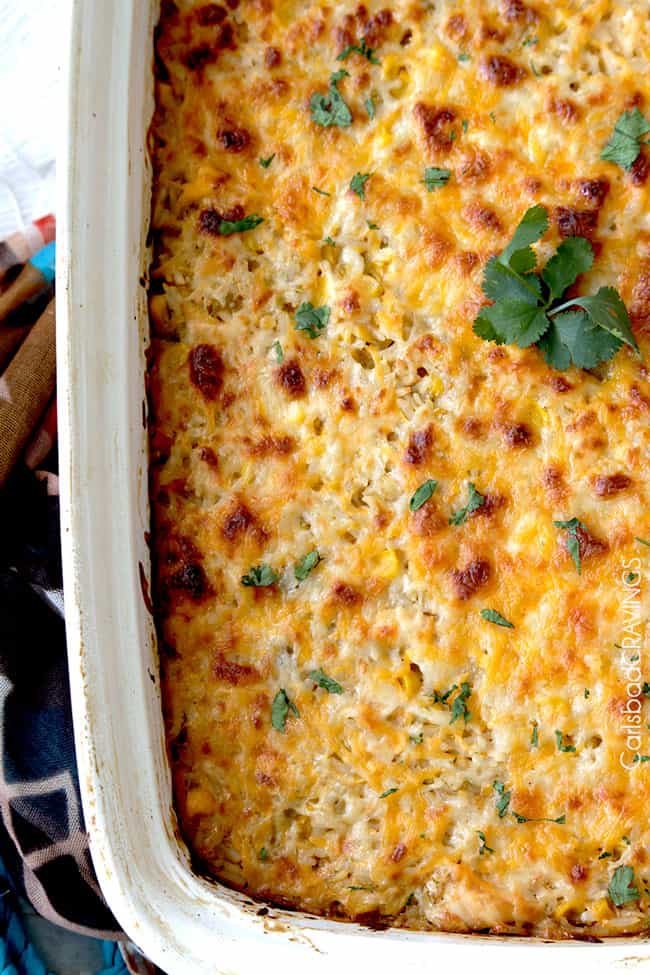 Top view of Salsa Verde Honey Lime Chicken and rice casserole with cheese on top in a white casserole dish garnished with parsley.