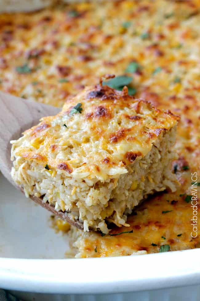 Salsa Verde Honey Lime Chicken and rice with cheese on top in a white casserole dish with a serving on a spoon.