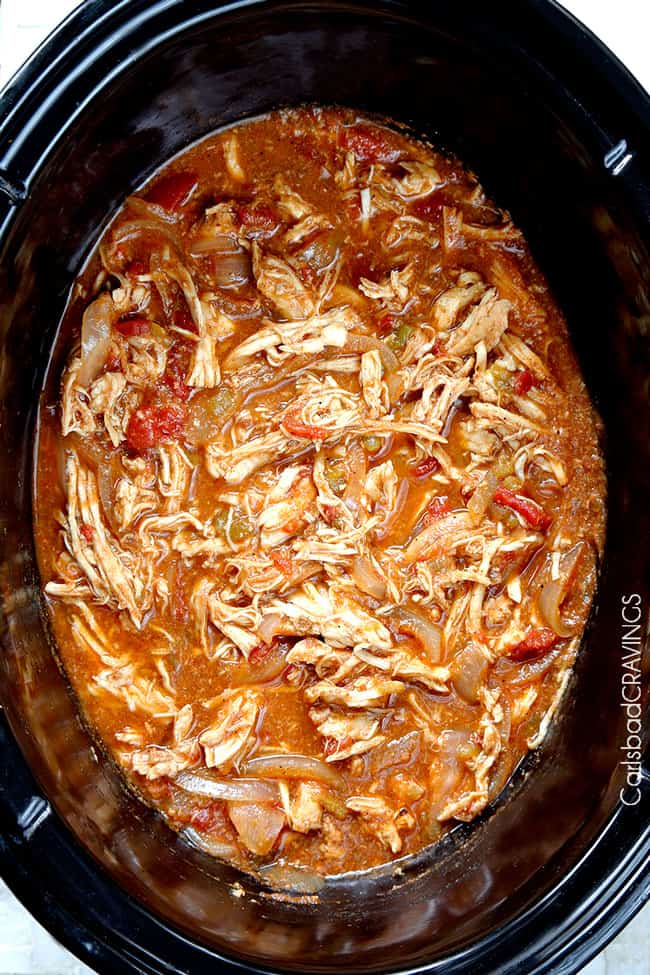 Crockpot Chicken Fajitas are the easiest way to make restaurant delicious chicken fajitas at home! Dump and simmer while you take a nap and let the citrus fiesta bath tenderize your chicken. showing how to make crockpot chicken fajitas by shredding chicken in slow cooker