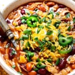 showing how to serve chicken chili by adding cheese, sour cream, green onions and tortilla chips