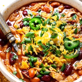showing how to serve chicken chili by adding cheese, sour cream, green onions and tortilla chips