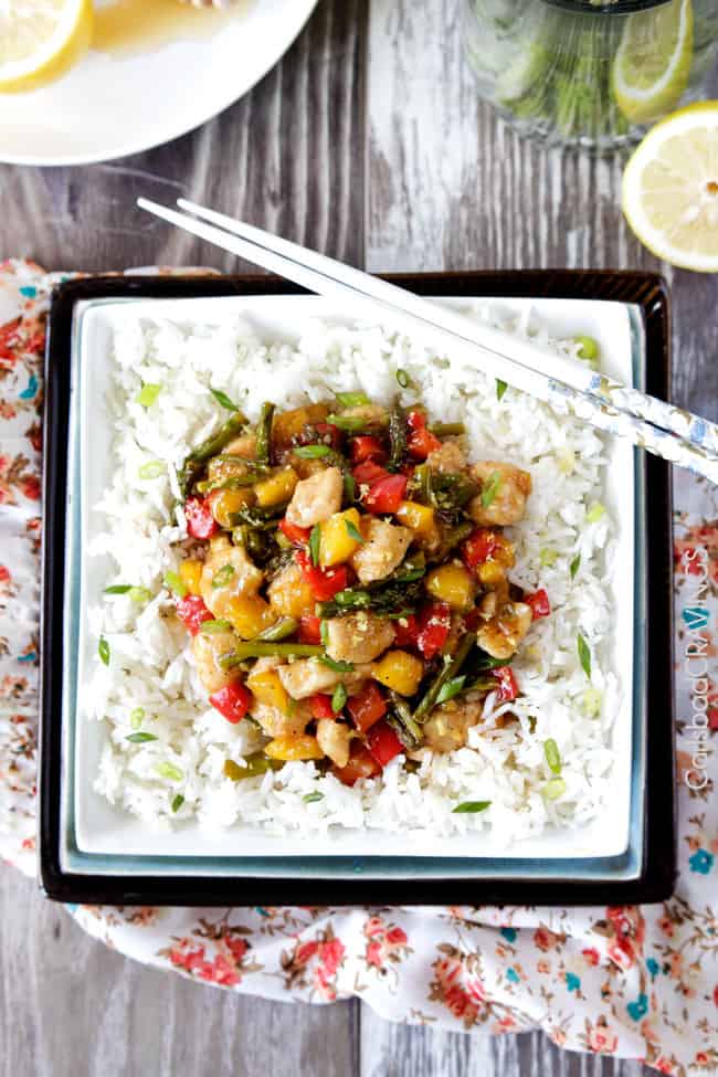 Top view of Honey Lemon Chicken Stir Fry over white rice in a bowl with chopsticks.