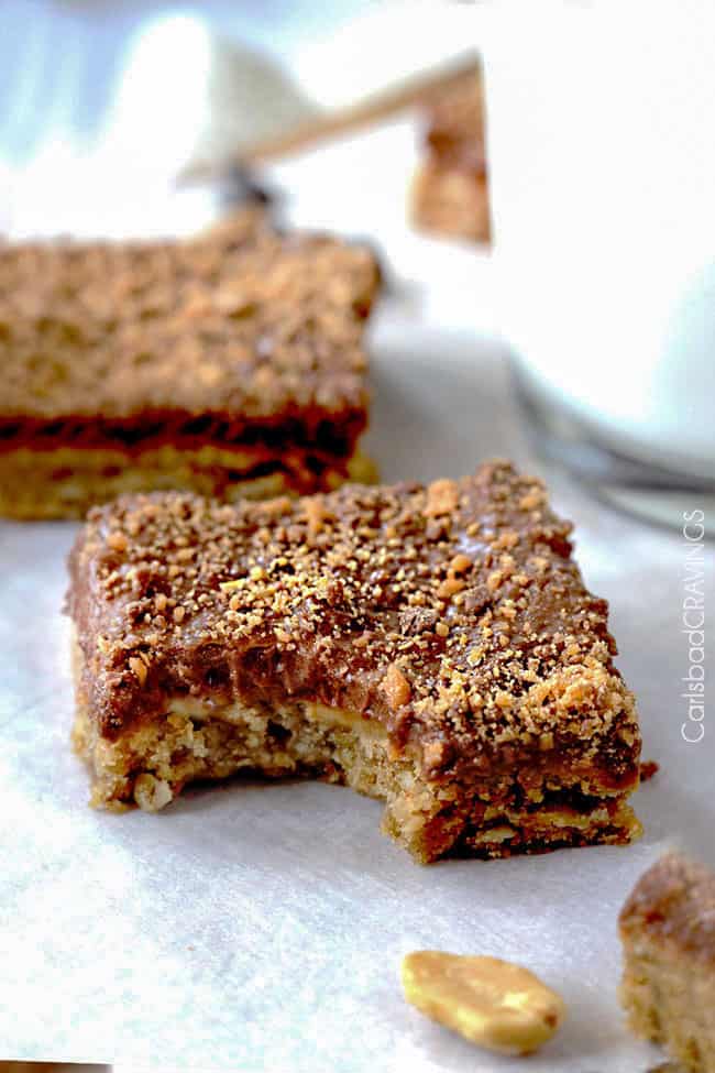 Close up of two Single Peanut Butter Cookie Bars with a bit out of it next to a cup of milk.