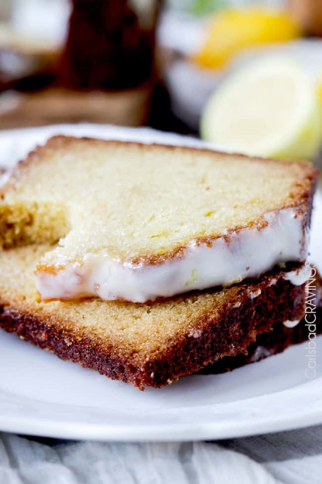moist lemon bread with a bite taken out of a slice on a white plate