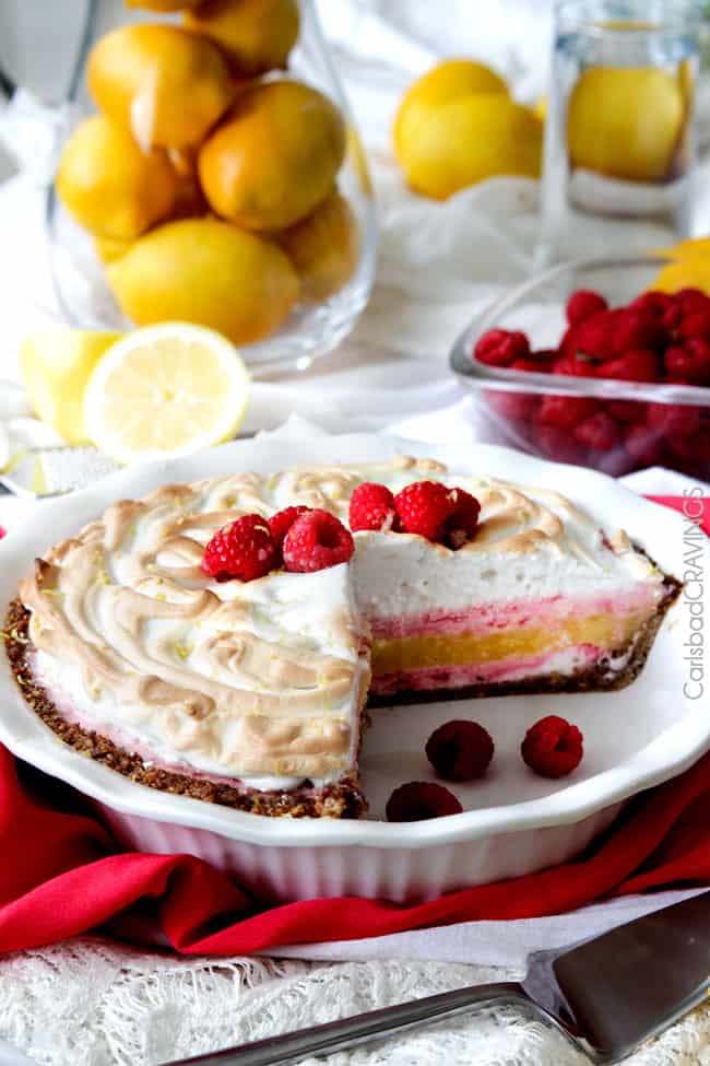 Frozen Lemon Meringue Pie on raspberries and a slice missing.