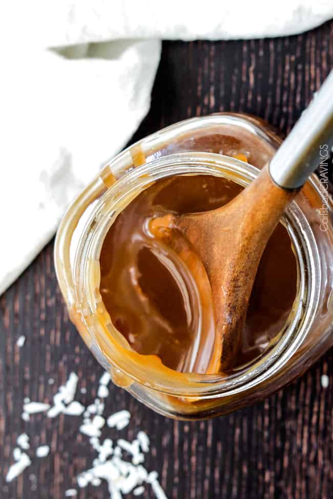 Top view of Coconut Caramel Sauce in a clear jar and serving spoon.