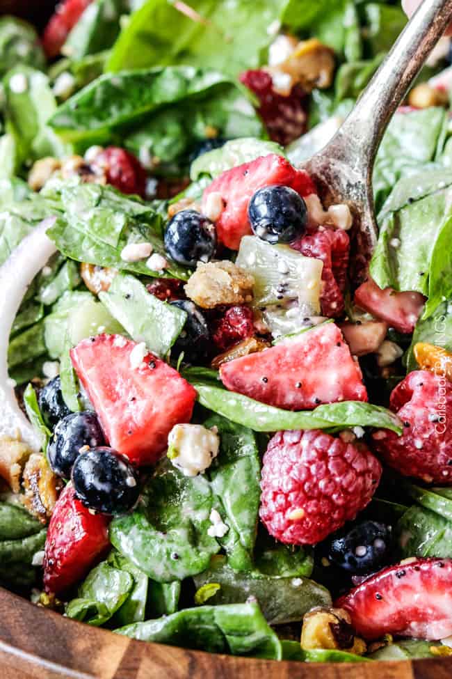 close up of a forkful of spinach berry salad tossed in a strawberry poppyseed dressing