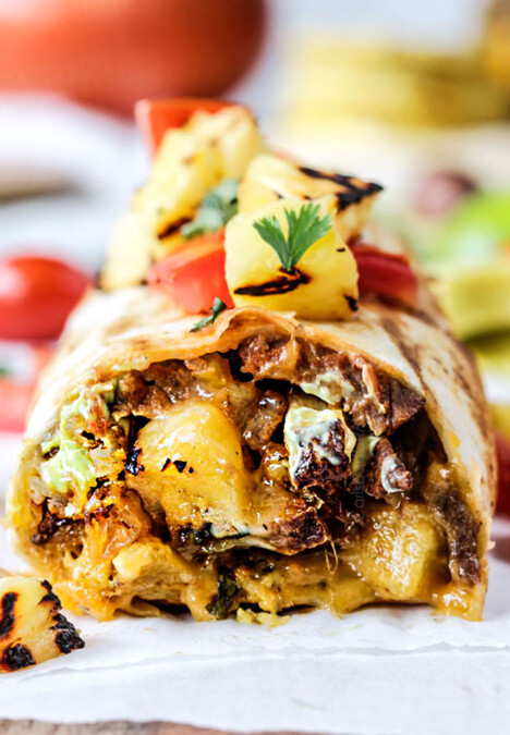 up close front view of a California Burrito with french fries, carne asada, sour cream and guacamole