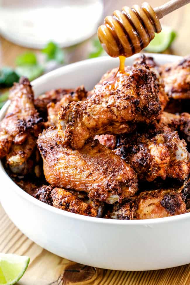 SHowing how to make Baked Chipotle Honey Lime Hot Wings by adding honey to the wings.
