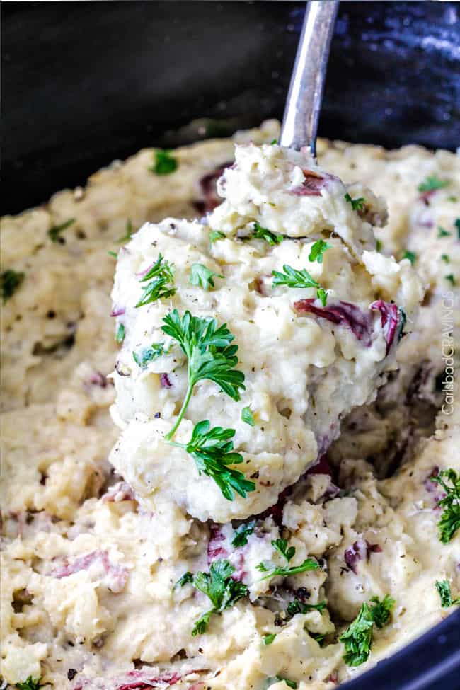 Mega creamy, mega flavorful, mega easy make-ahead Slow Cooker Mashed Potatoes are about to become your favorite go-to mashed potatoes. You will never need to peel or boil potatoes again! up close of a spoon full of easy crockpot mashed potatoes