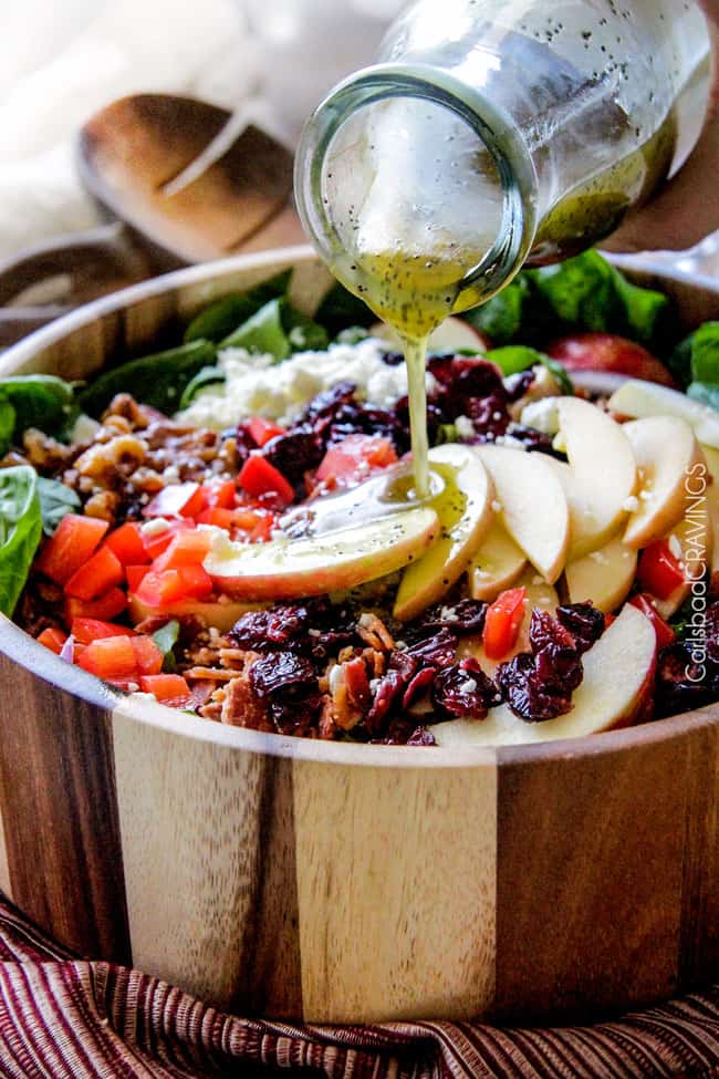 showing how to make Apple Salad by pouring apple vinaigrette over salad