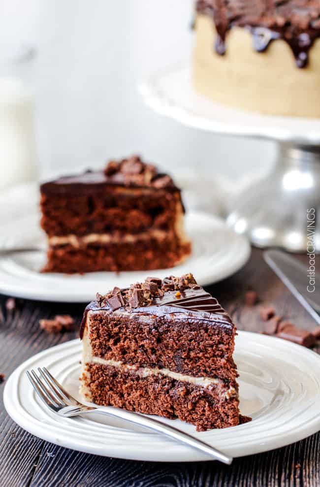 two slices of chocolate caramel cake on white plates with forks.