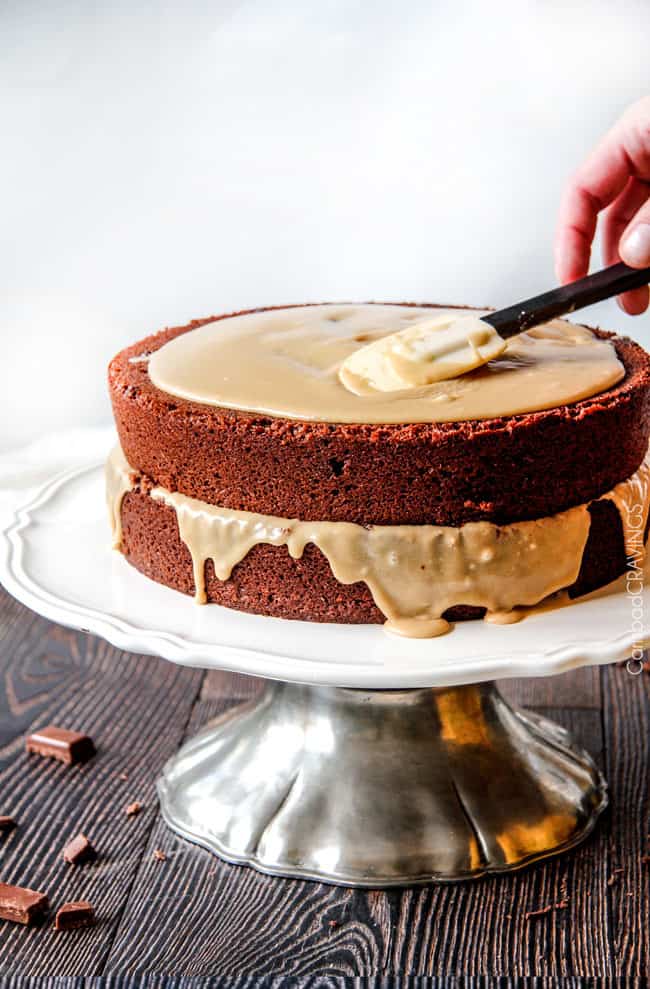 process shot showing caramel buttercream frosting being smoothed over chocolate cake layers