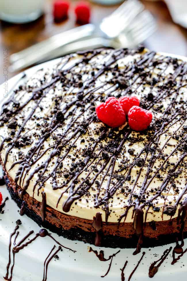 Full Peanut Butter Chocolate Mousse cake on a plate with raspberries and drizzle.