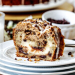 The best Banana ANYTHING ever! Moist Banana Coffee Cake riddled with chocolate chips and walnuts (optional) with an INCREDIBLY creamy cheesecake-like cream cheese filling all topped with brown sugar walnut streusel and vanilla drizzle.