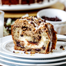 The best Banana ANYTHING ever! Moist Banana Coffee Cake riddled with chocolate chips and walnuts (optional) with an INCREDIBLY creamy cheesecake-like cream cheese filling all topped with brown sugar walnut streusel and vanilla drizzle.